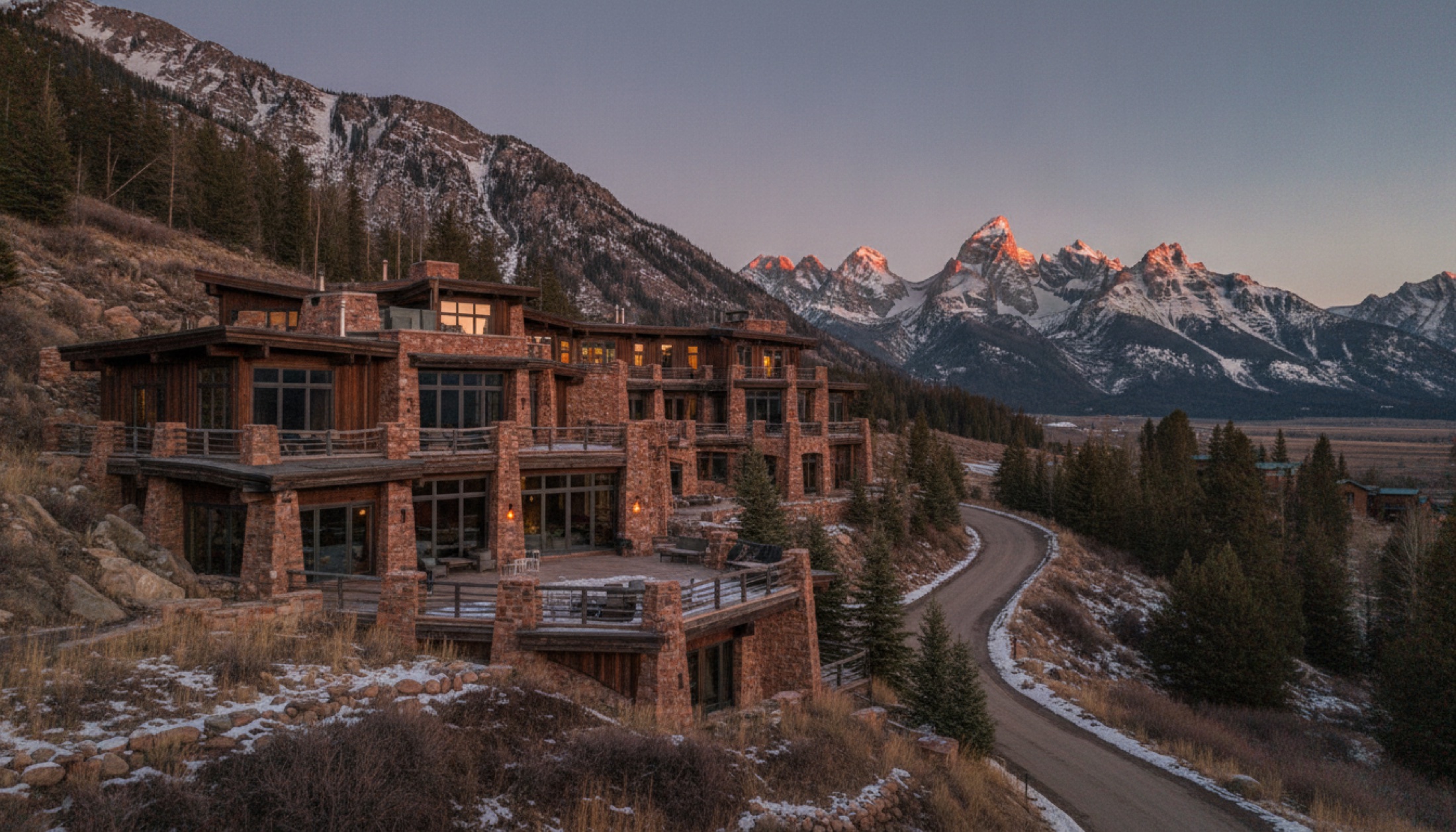 Amangani'nin Jackson Hole'daki kırmızı kumtaşı ve köknar cephesi, arka planda Grand Teton zirveleri