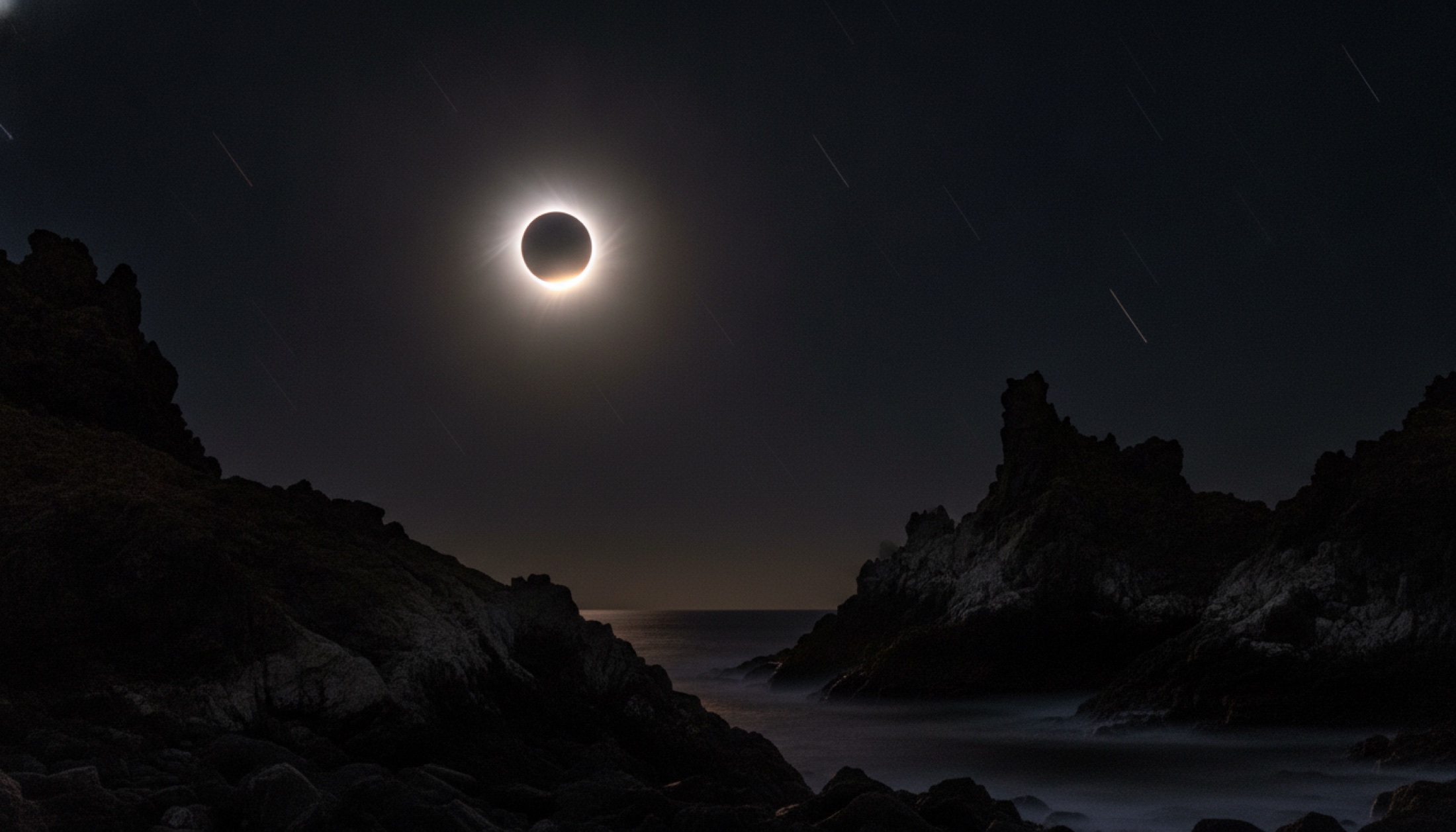 12 Ağustos 2026 toplam güneş tutulması — volkanik kayalıklar üzerinde korona halkası ve Perseid meteor izleri
