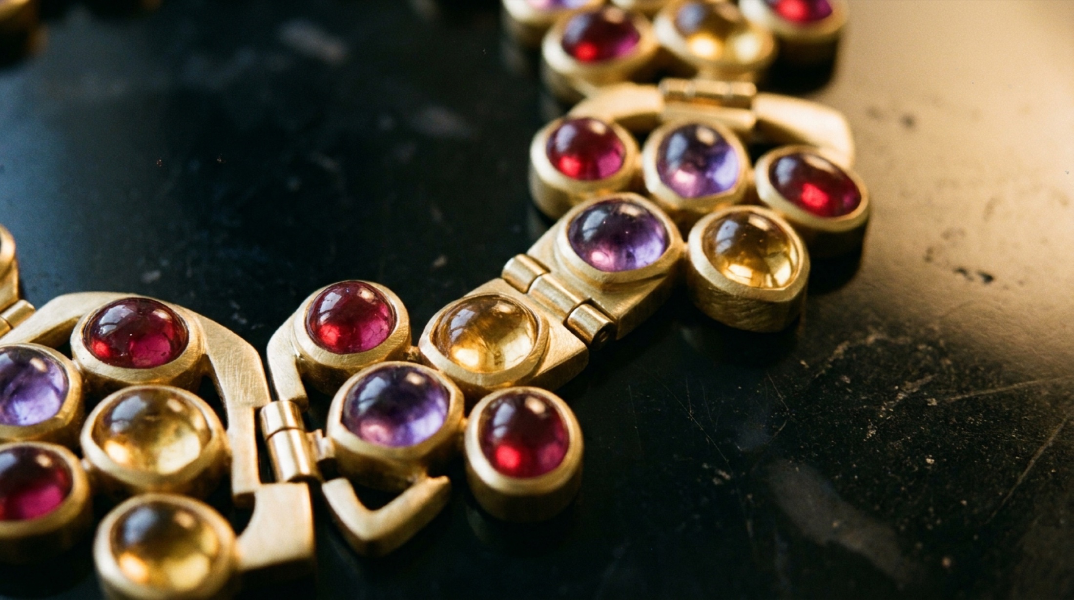 Bulgari Eclettica koleksiyonundan bir parçanın makro detayı: kabochon kesim renkli taşlar metal çerçeve içinde, parçanın dönüşebilir menteşe mekanizması görünür halde