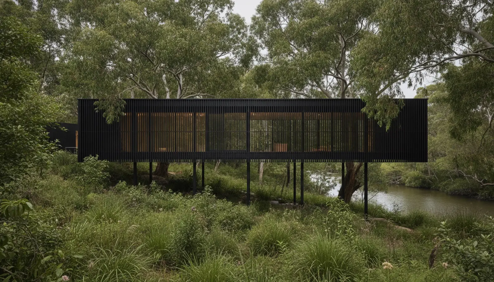 Edition Office'in Melbourne Kew'deki House in a Garden konutu — siyah ahşap kafes cephe, Yarra nehri kıyısında ağaç tepeleriyle aynı kotta yükselen iki kanatlı yapı.