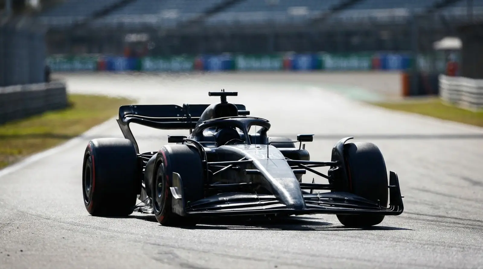 Islak asfalt üzerinde pit lane boyunca uzanan motor ünitelerinin parçaları, teknisyen elleri ve alüminyum yüzeyler, endüstriyel ışık