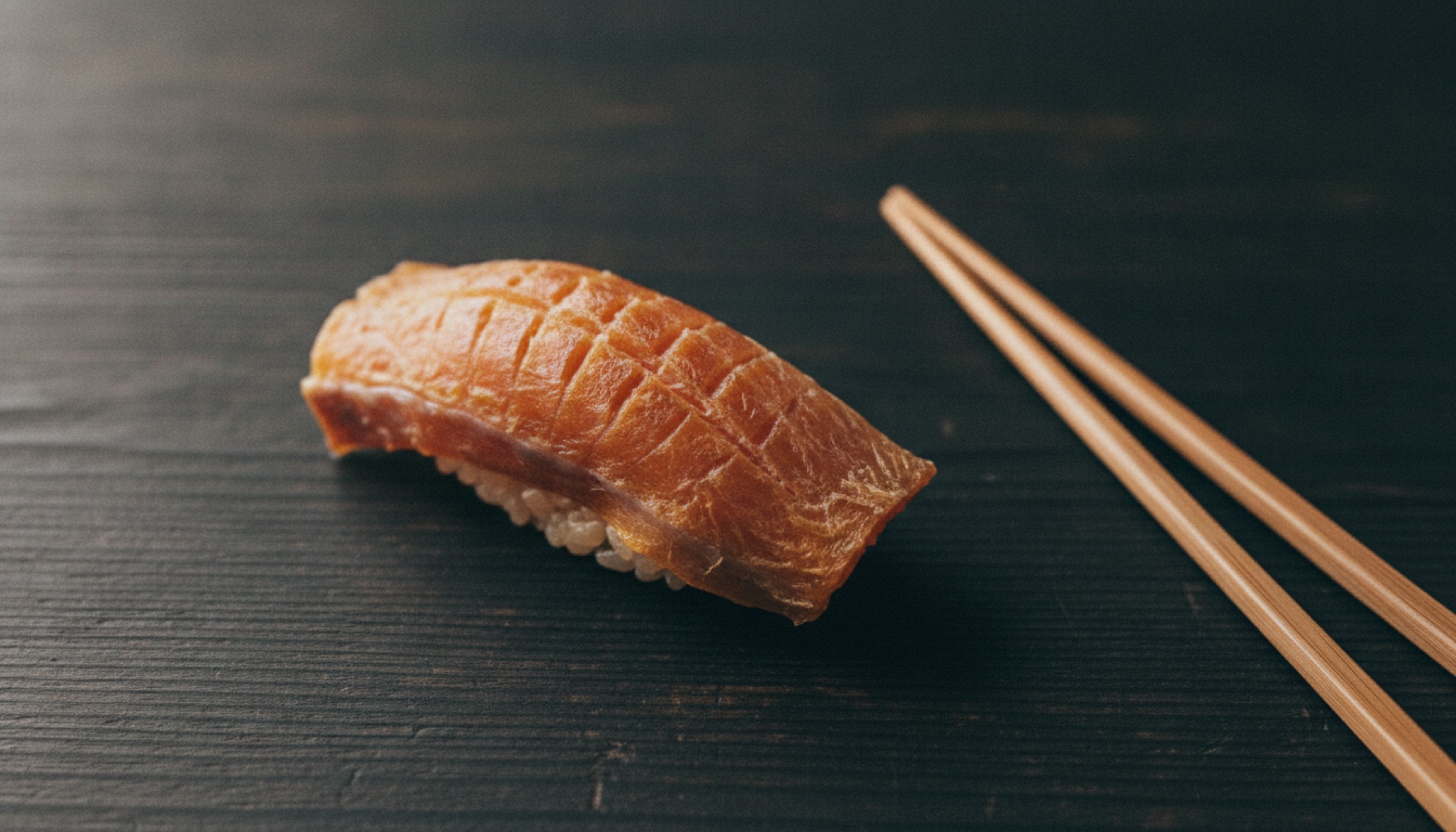 Koji Kimura'nın Sushi Kimura restoranında hinoki ahşap tezgah üzerinde sunulmuş tek bir yaşlandırılmış nigiri: kehribar-turuncu yüzeyiyle elli beş gün bekletilmiş kılıç balığı.