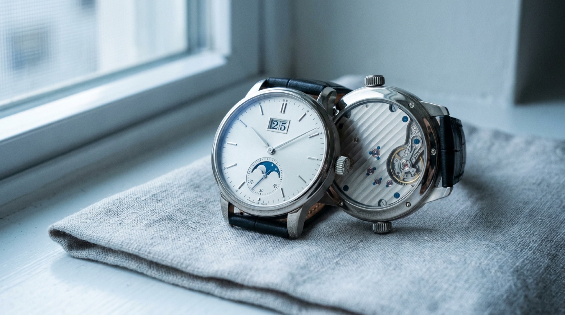 A. Lange & Söhne Saxonia Annual Calendar 36mm beyaz altın, gümüş argente kadran ve büyük tarih göstergesiyle makro detay, Glashütte ribbing'li plakalar caseback aracılığıyla görünür