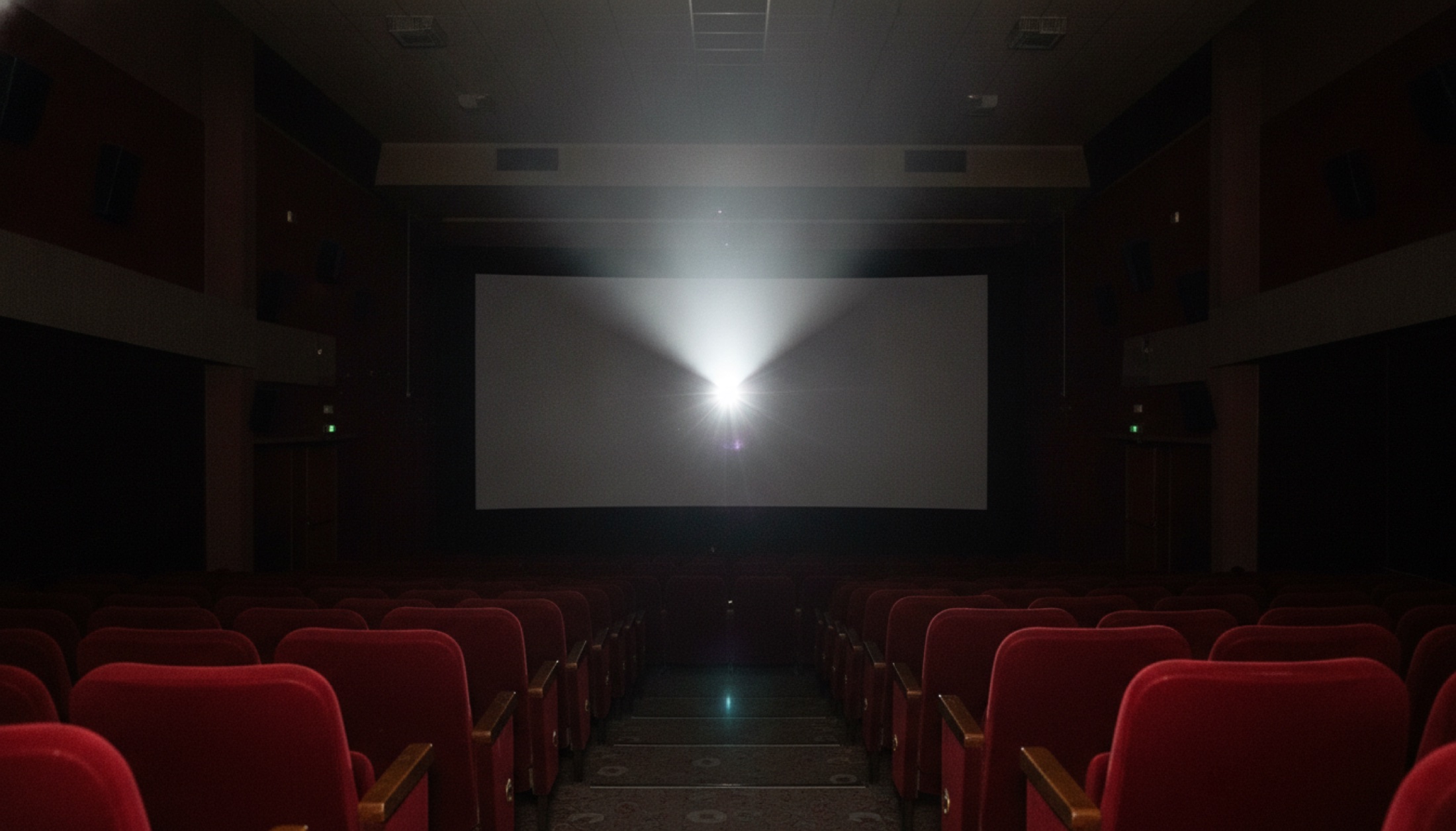 Boş sinema salonunda projeksiyon huzmesi karanlıkta ekrana uzanıyor