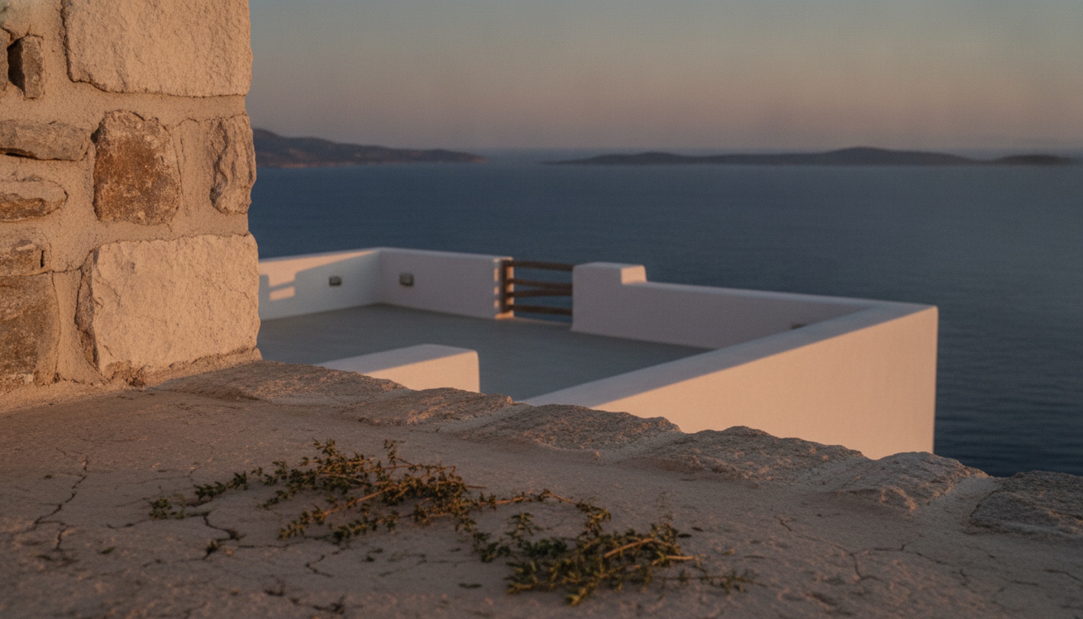 Paros'ta kayalık üstünde beyaz badanalı Cycladic teras, alacakaranlıkta Ege manzarası