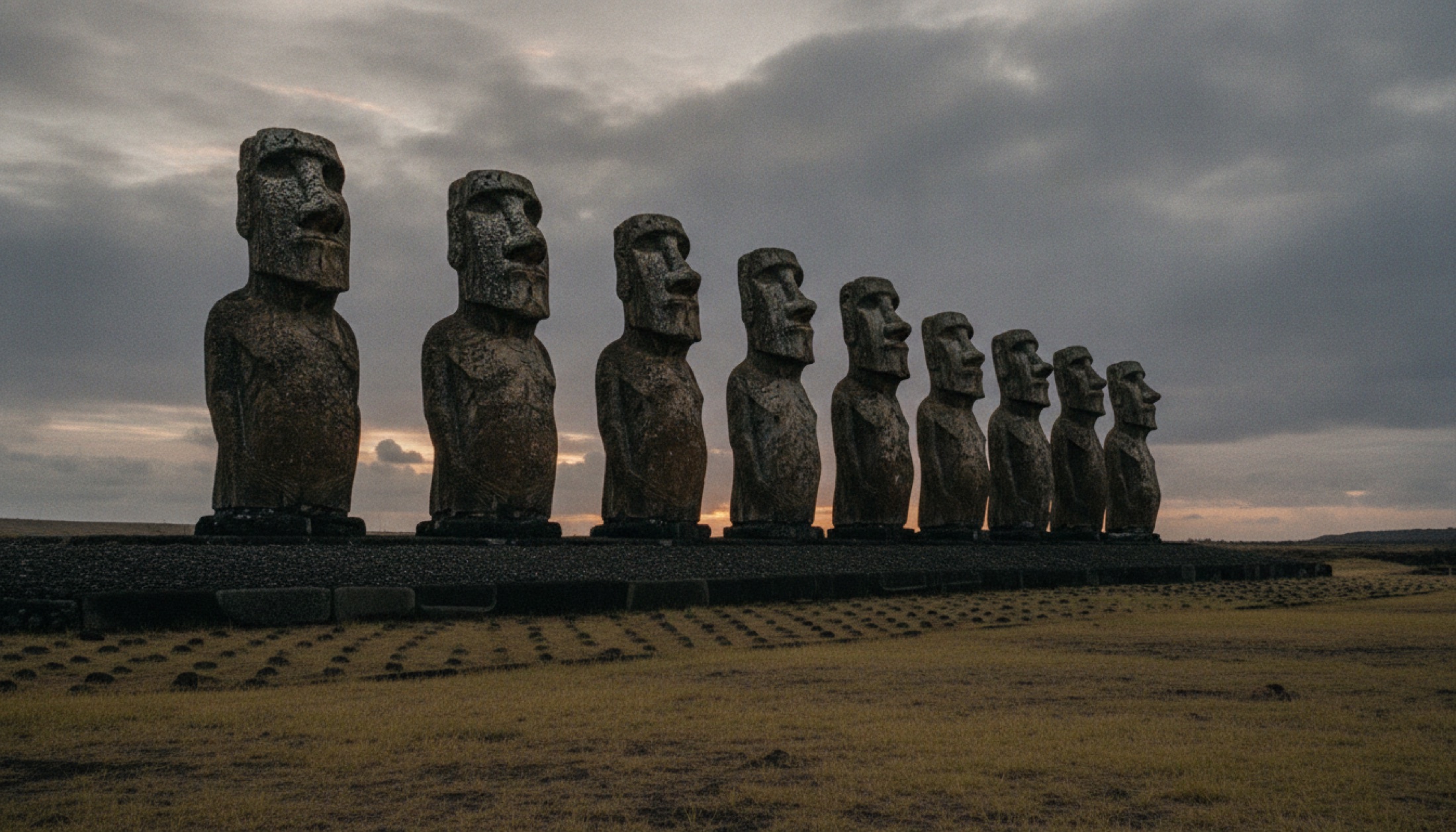 Pasifik Okyanusu'nun ortasında, alacakaranlık ışığında sıralanan moai heykelleri — Wild Horse Nine'ın çekildiği Easter Island'dan bir atmosfer