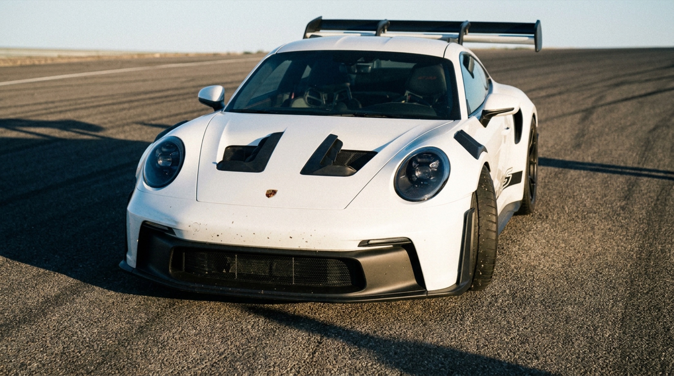 Porsche 992 GT3 RS büyük arka kanat açık, pist düzlüğünde önden görünüm