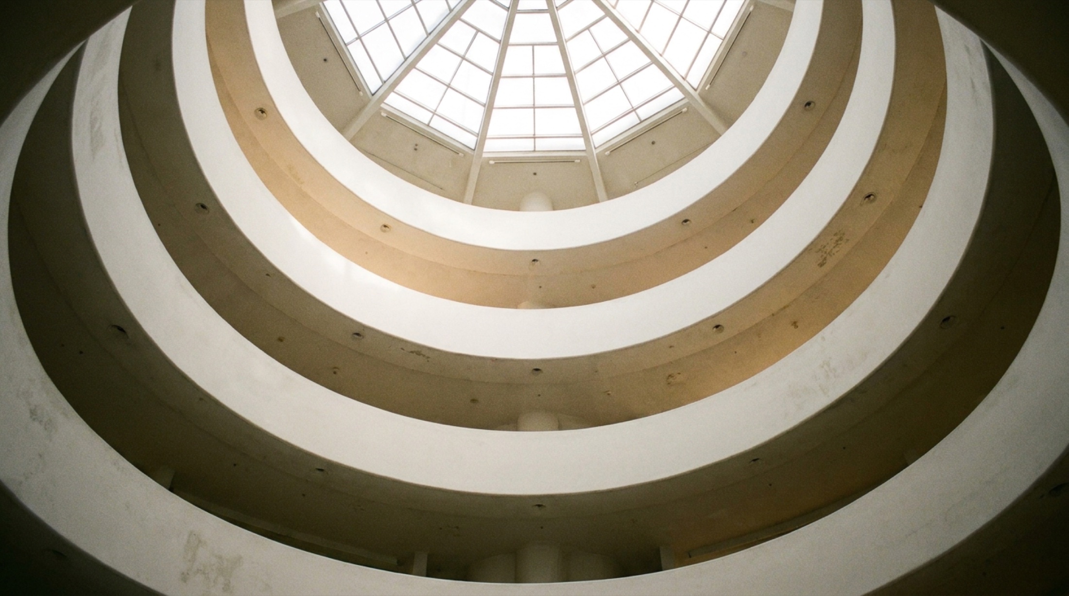 Frank Lloyd Wright'ın spiral mimarisini yukarıdan gösteren boş Guggenheim rotundası; beyaz eğimli rampalarda ışık oyunları