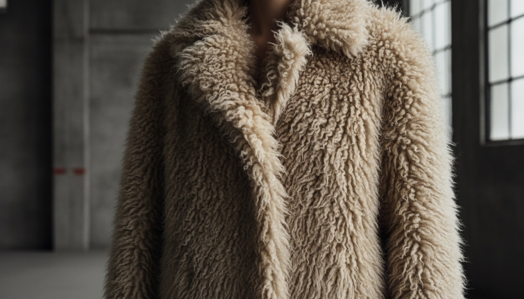 Bottega Veneta FW26 koleksiyonundan shearling paltunun dokusu, sert ışık altında Milano'nun sert mimarisiyle buluşuyor.